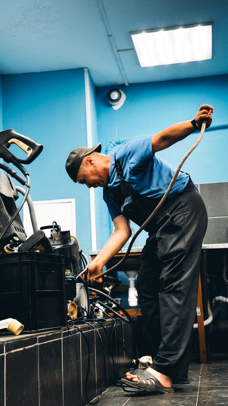 An Acme plumber clearing a drain under a home kitchen sink